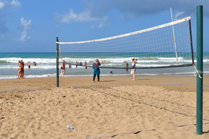 A volleyball net is mounted on the metal posts of beach