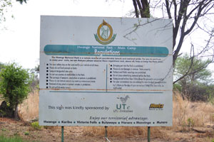 An information board reads: “Hwange National Park - Main Camp, Regulations”